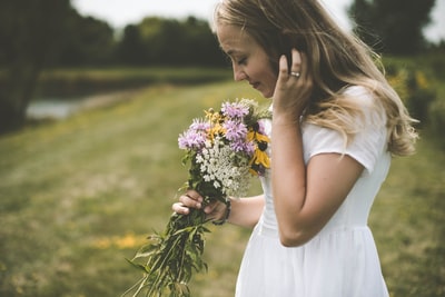 一名身穿白色衬衫、手持花环的妇女身上散发着花香